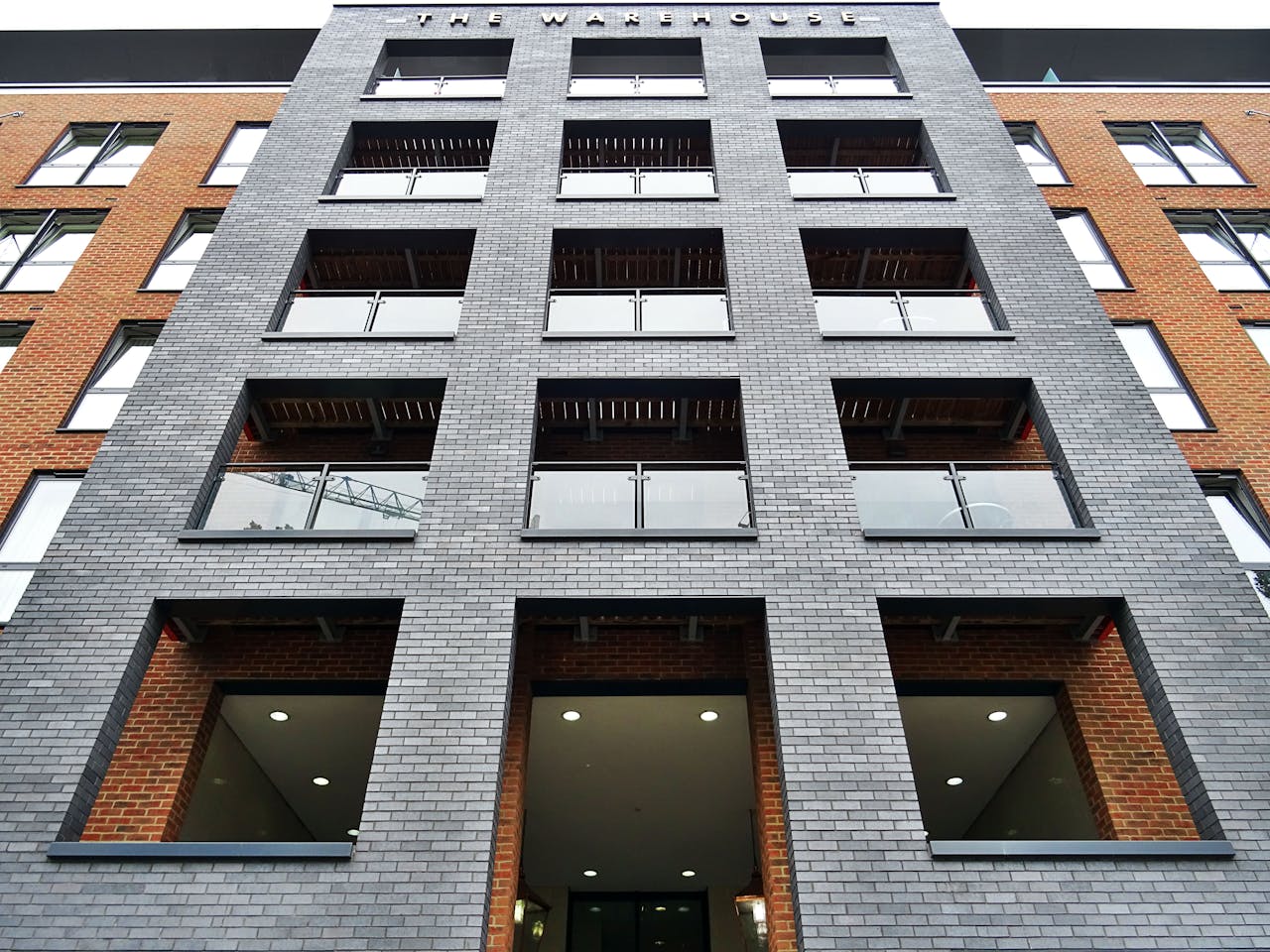 Low angle view of a modern brick building facade showcasing glass balconies and architectural design.